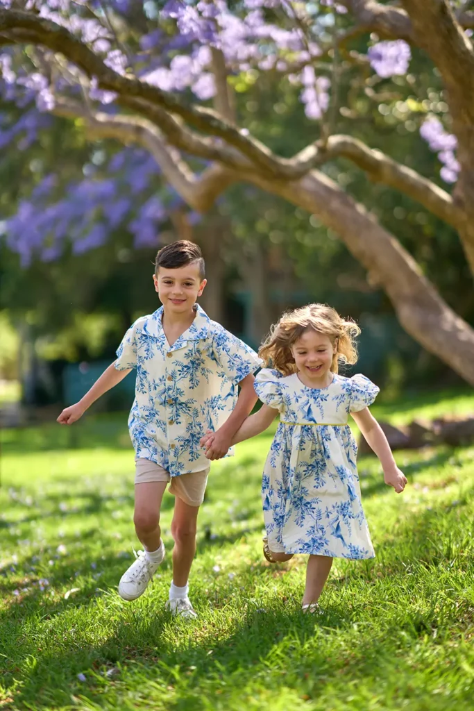 Happy children running under blooming purple jacaranda trees in Hornsby