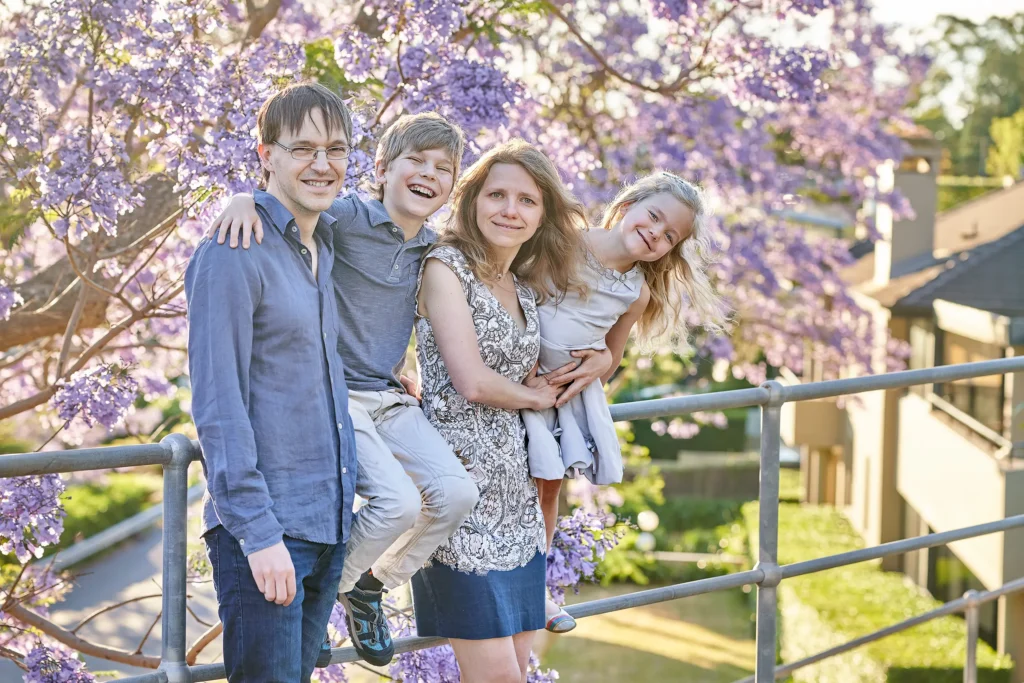 Parents with son and daughter under blooming jacaranda trees in Chadstwood