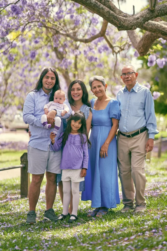 Multi-generation family smiling under jacarandas in Hornsby