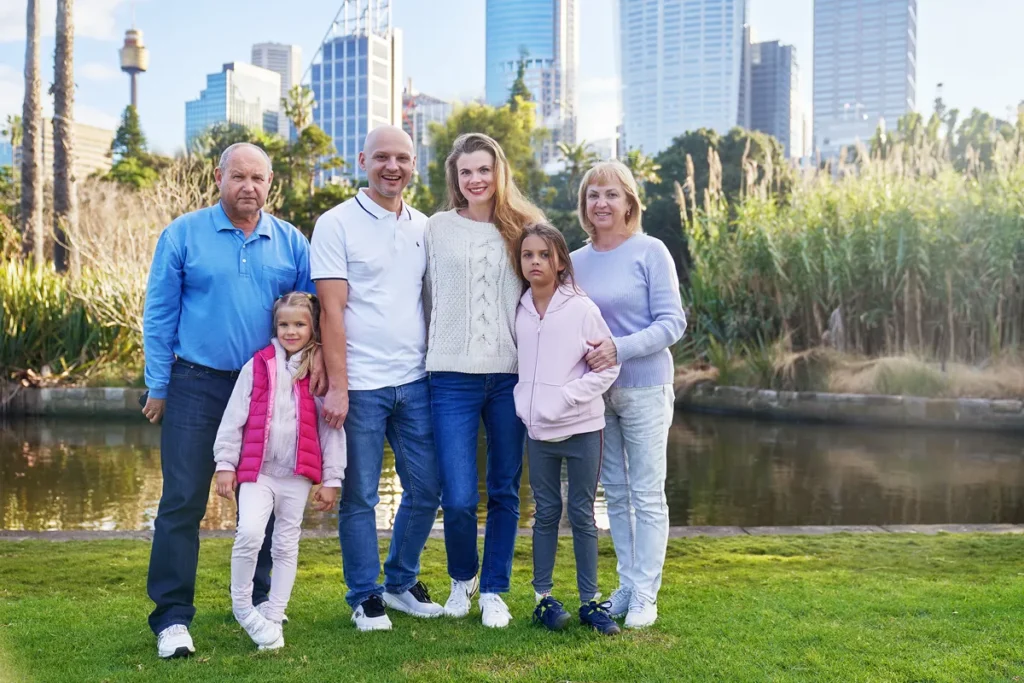 Extended family posing in Royal Botanic Garden with Sydney city skyline view.