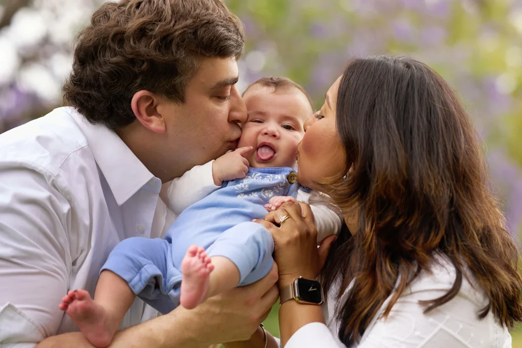 mum and dad kissing baby girl on the cheek