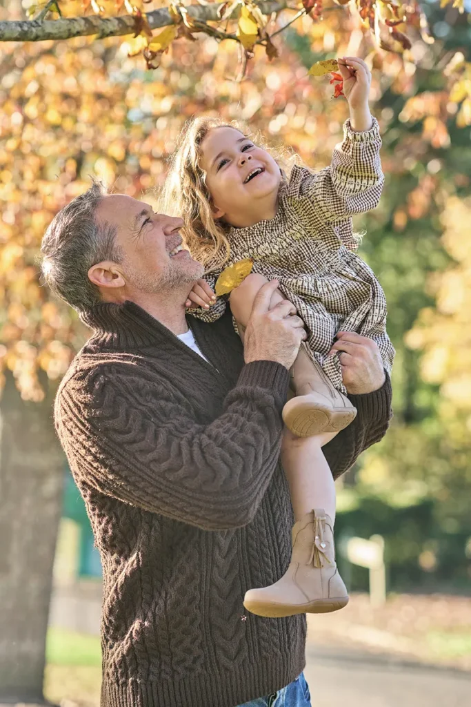 dad lifting younger daughter up high above his head