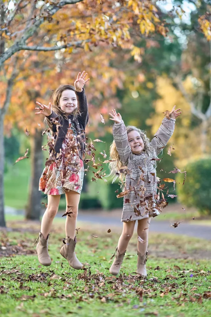 two sisters running and laughing together on open grass
