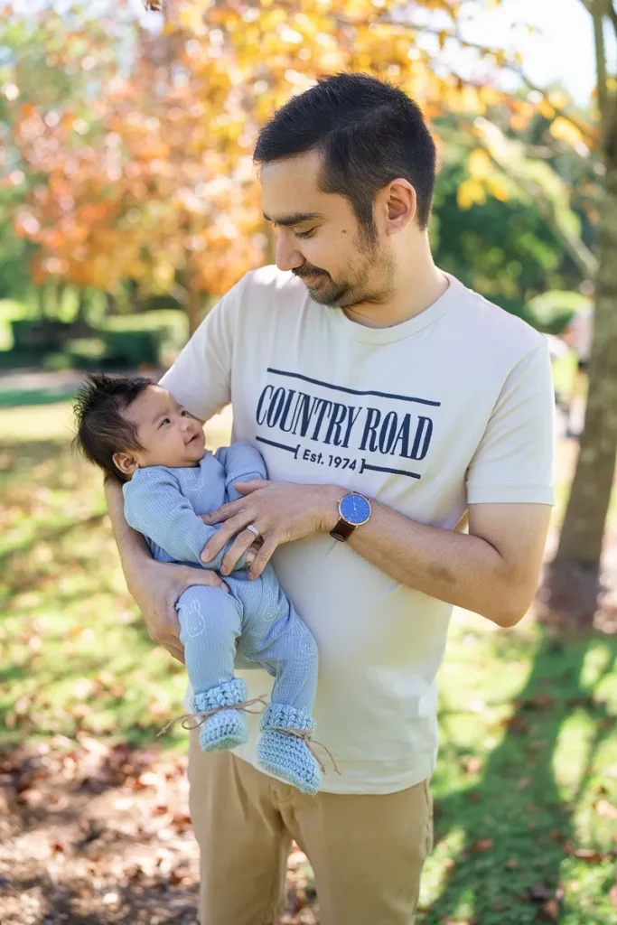 Father holding his son with golden autumn leaves background in Fagan Park