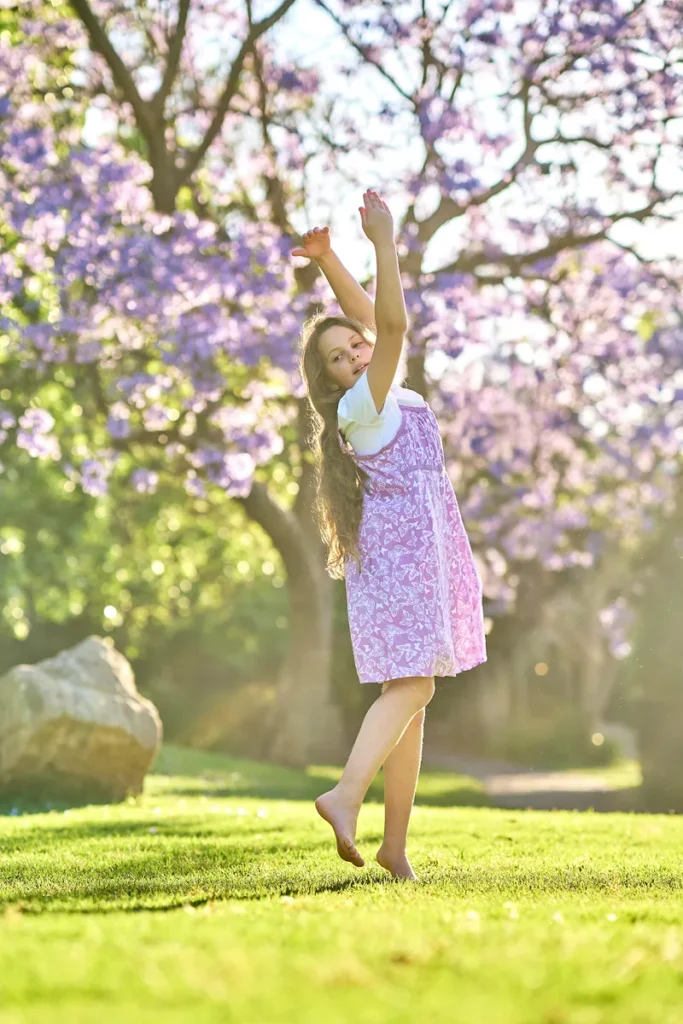 Girl dancing up to jacaranda blossoms in Hornsby