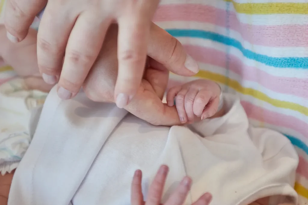 Newborn hand gripping an adult finger tightly