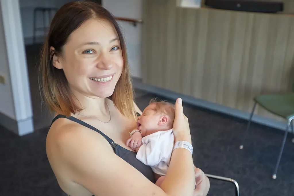 Mother smiling with newborn resting against her chest