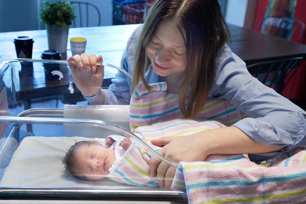 Mother adjusting blanket around sleeping newborn