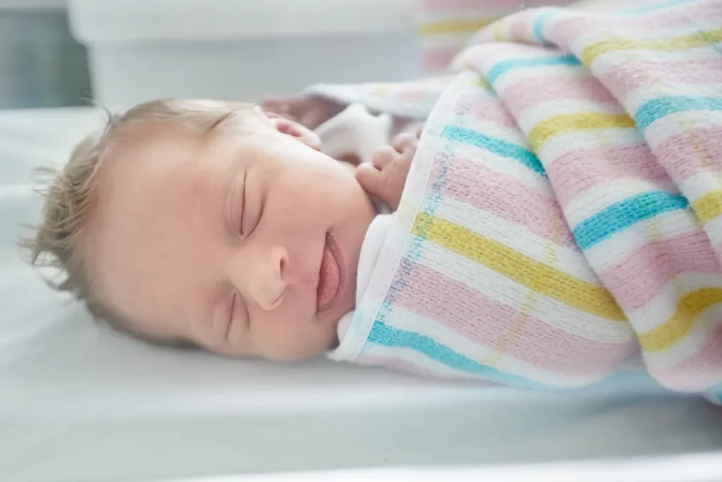 Newborn sleeping swaddled in hospital bassinet