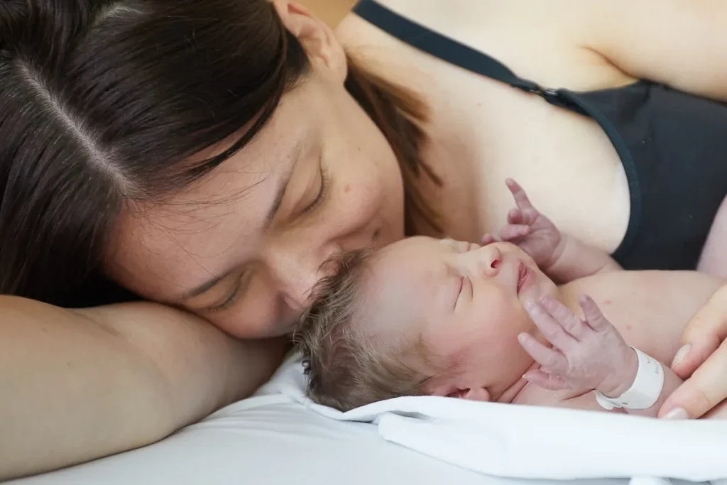 Mother kissing newborn while holding her close