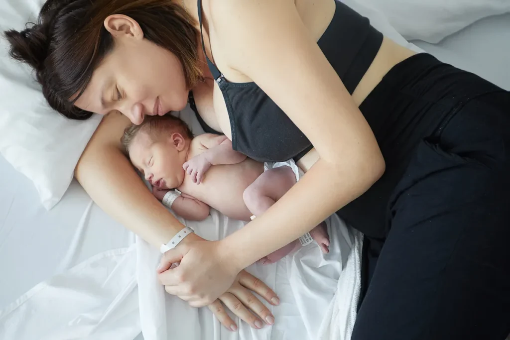 Mother lying back while holding newborn close
