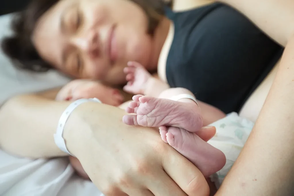 Mother cradling newborn closely on the bed