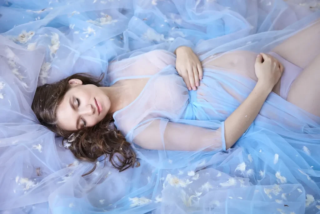 Pregnant woman lying on bed eyes closed