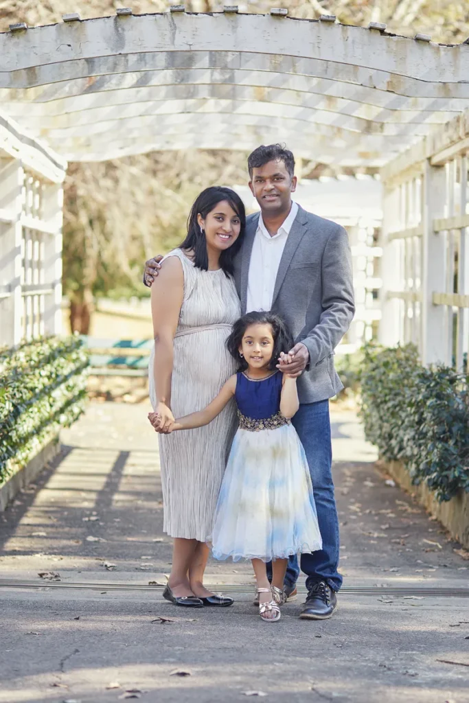 family of three posing together in garden walkway