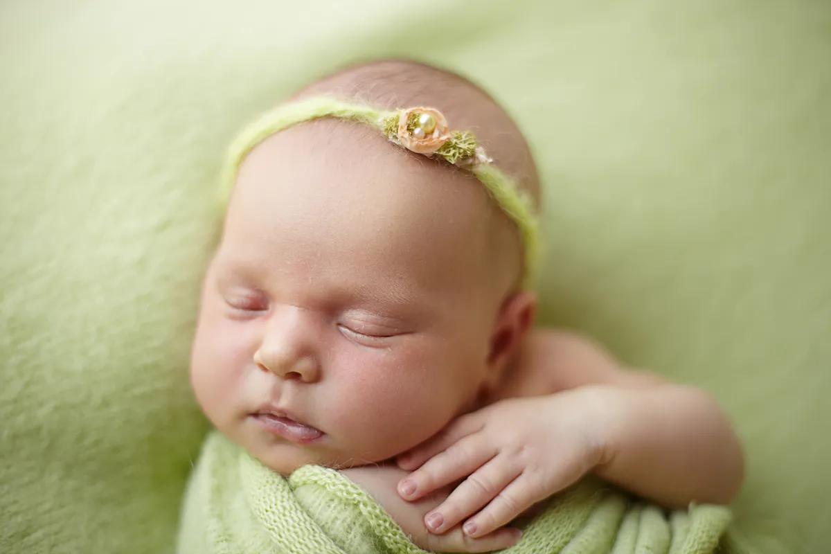 newborn in yellow headband sleeping on blanket Hornsby