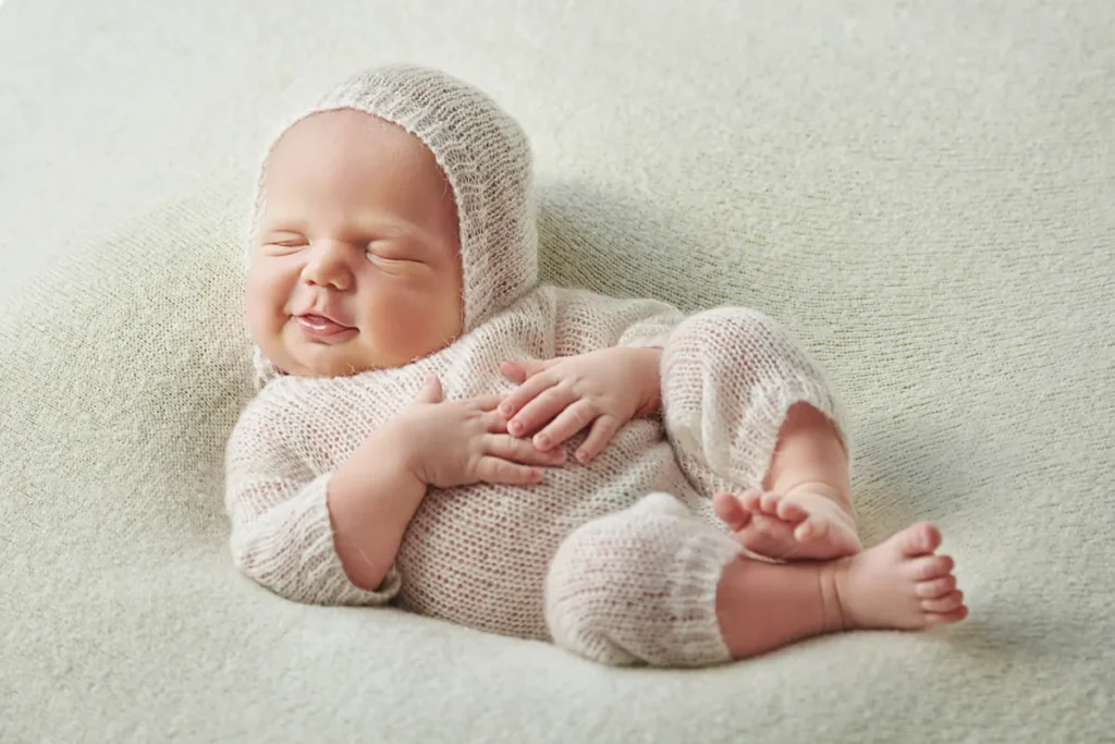 newborn in beige bonnet sleeping on white wrap