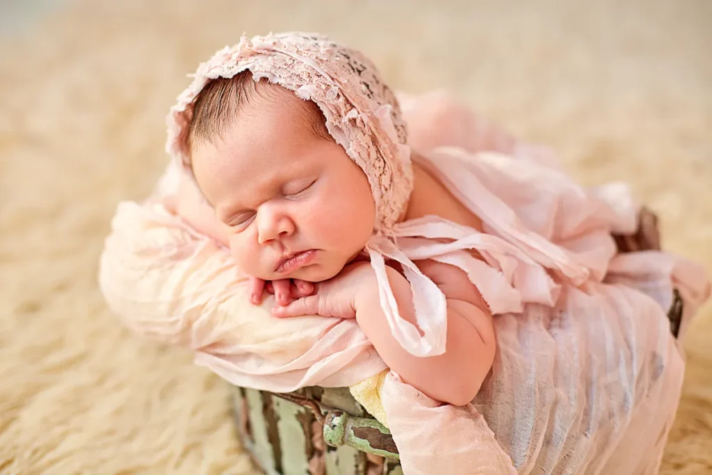 sleeping baby girl in lace headband on tan backdrop