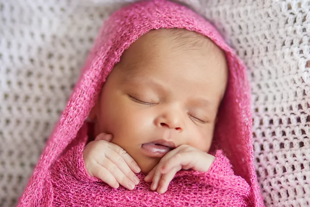 baby wrapped in pink on textured backdrop