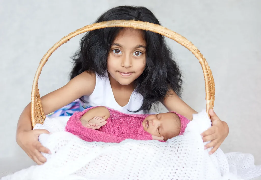 young girl holding newborn in wicker basket