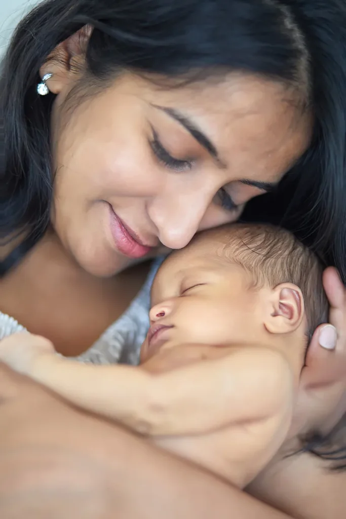 mother smiling over sleeping wrapped newborn