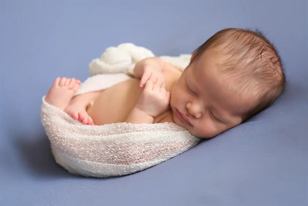 sleeping baby in round wicker basket on grey