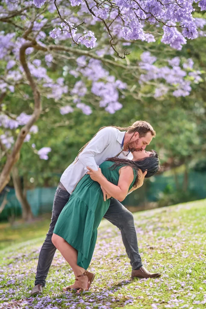 A couple kissing under jacarandas in at Hornsby
