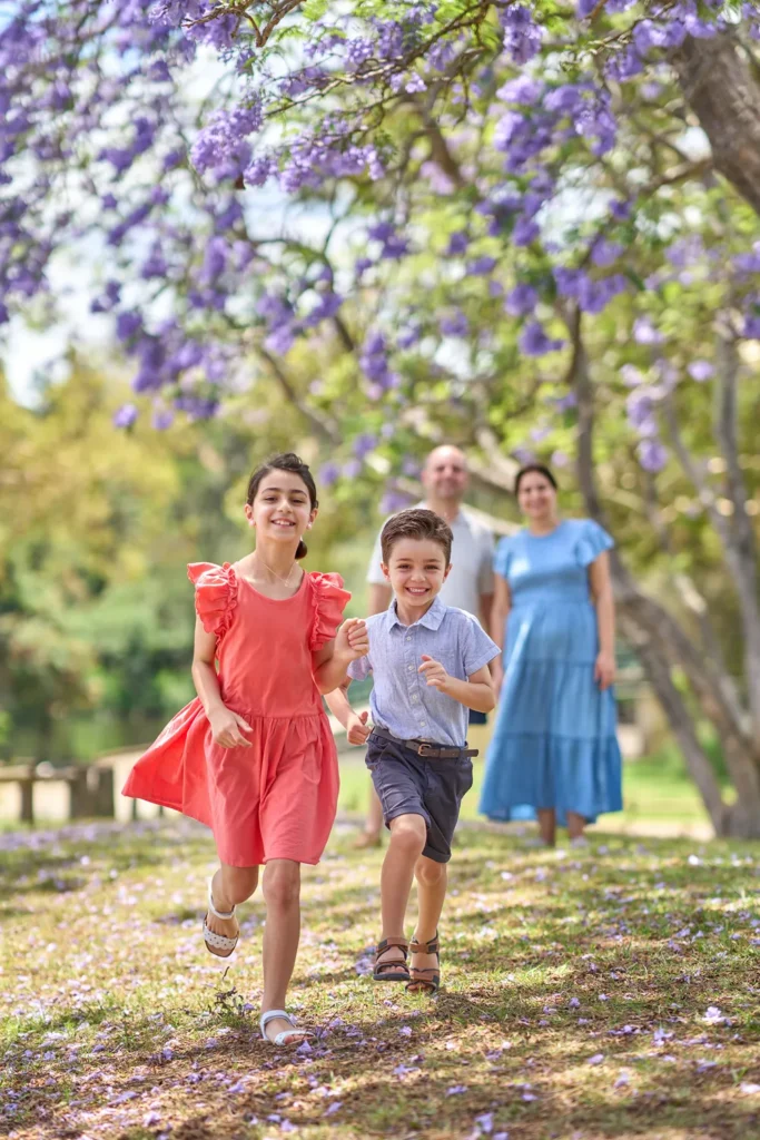 Children run beneath jacaranda at Parramatta Park