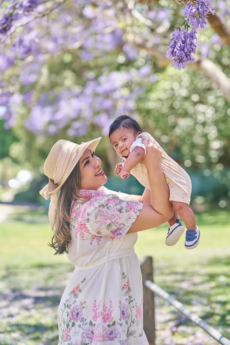 Mother lifting baby under tree