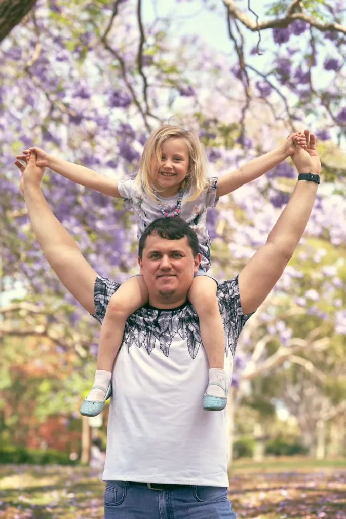 Father carrying daughter on shoulders outdoors