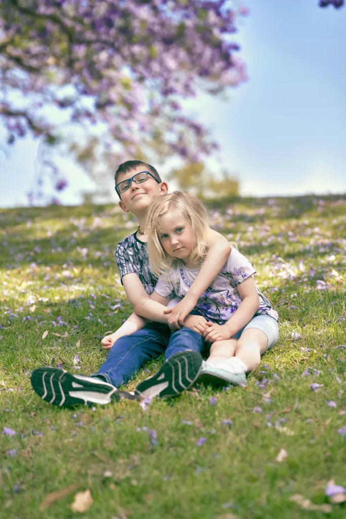 Two children sitting together on grass