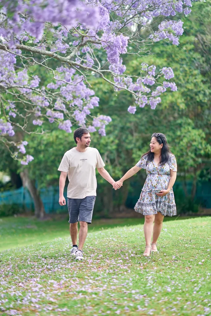 Expecting mother walking under jacaranda trees