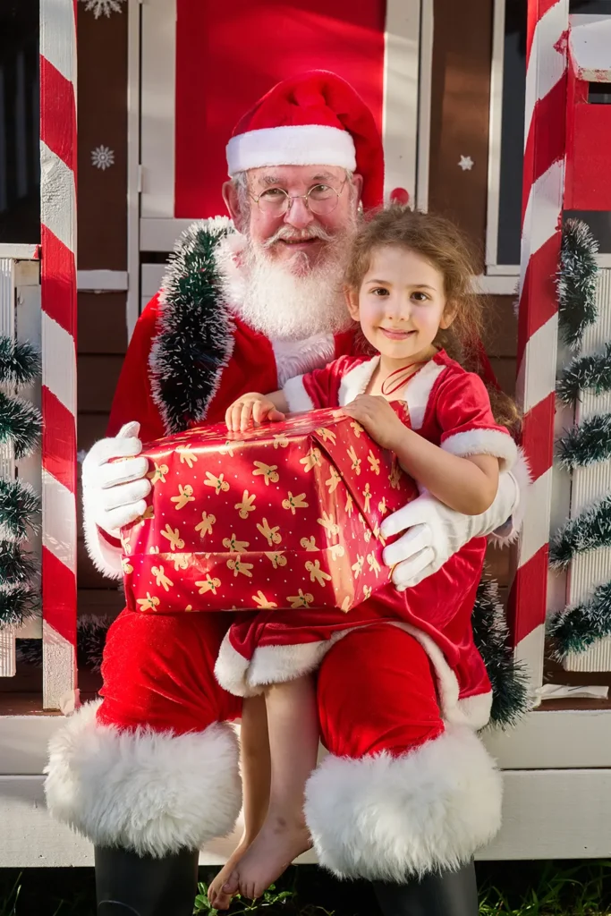 Girl sits with Santa holding gift